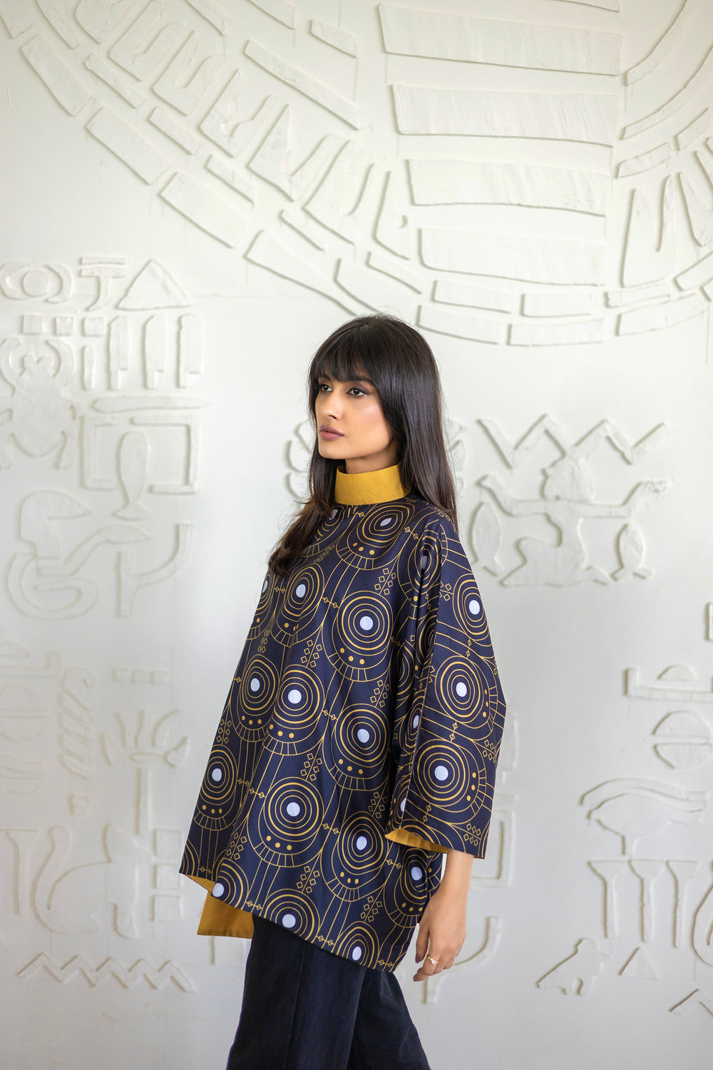 Woman wearing a patterned top against an abstract white wall