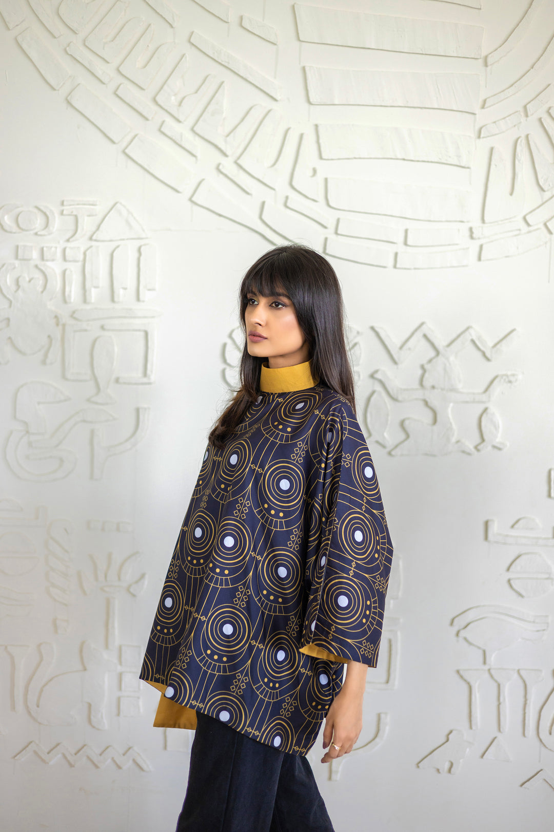 Woman wearing a patterned top against an abstract white wall