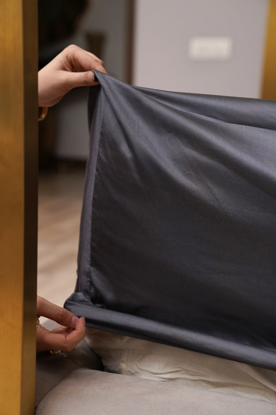 Person holding a dark gray fabric against a neutral background
