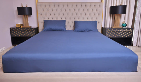 Bed with blue bedding and pillows in a bedroom setting with nightstands and lamps.