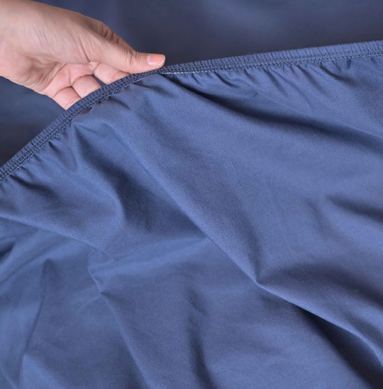 Close-up of a hand holding blue fabric with a plain background
