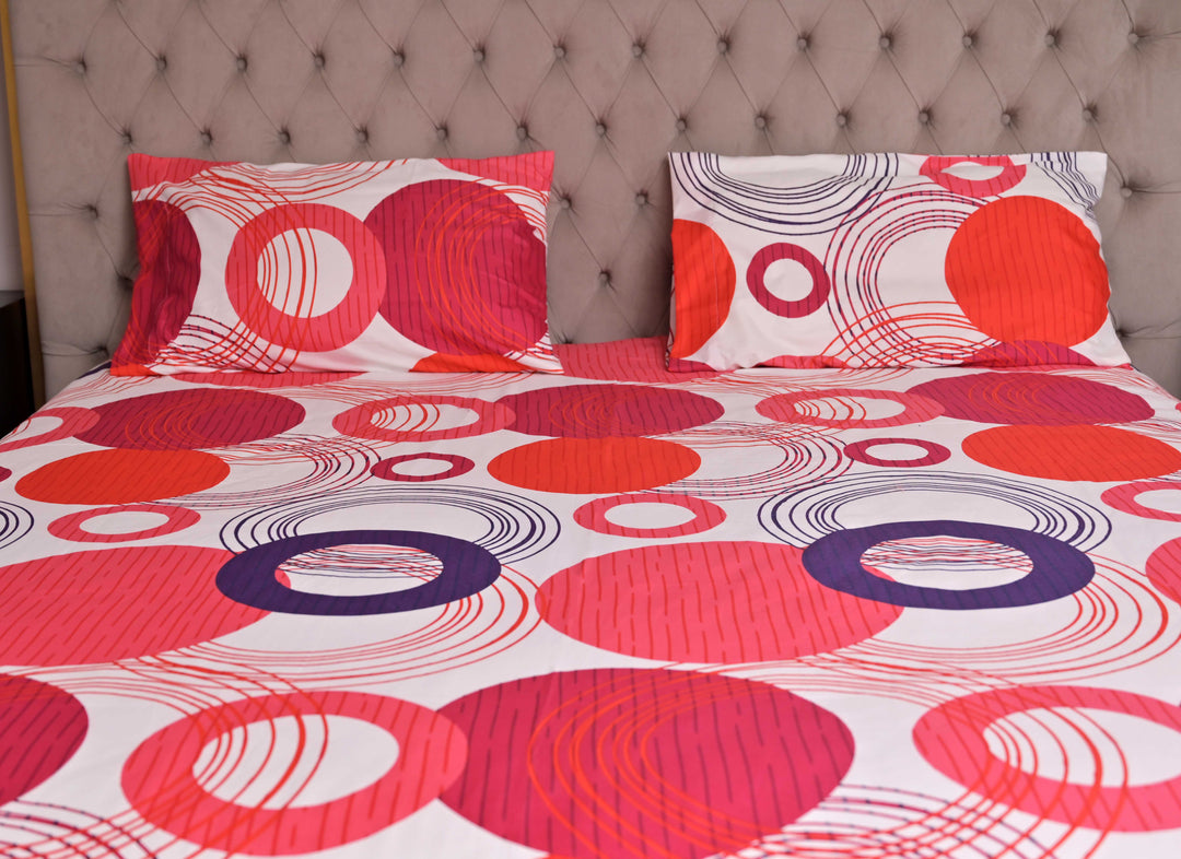 Bedspread with circular patterns on a bed against a tufted headboard.
