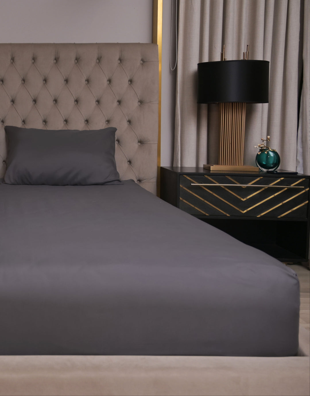Gray bedspread on a bed with matching pillows in a bedroom setting.