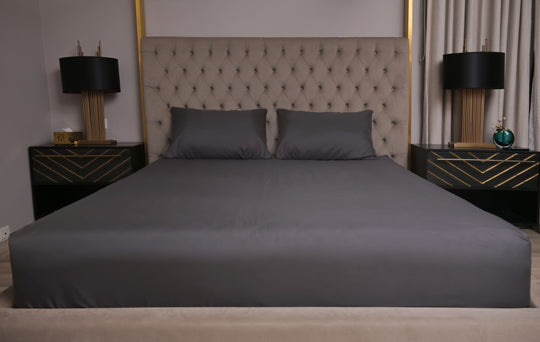 Gray bedspread on a bed with matching pillows in a bedroom setting.