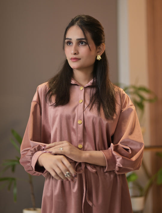 Woman wearing a pink dress with a blurred indoor background