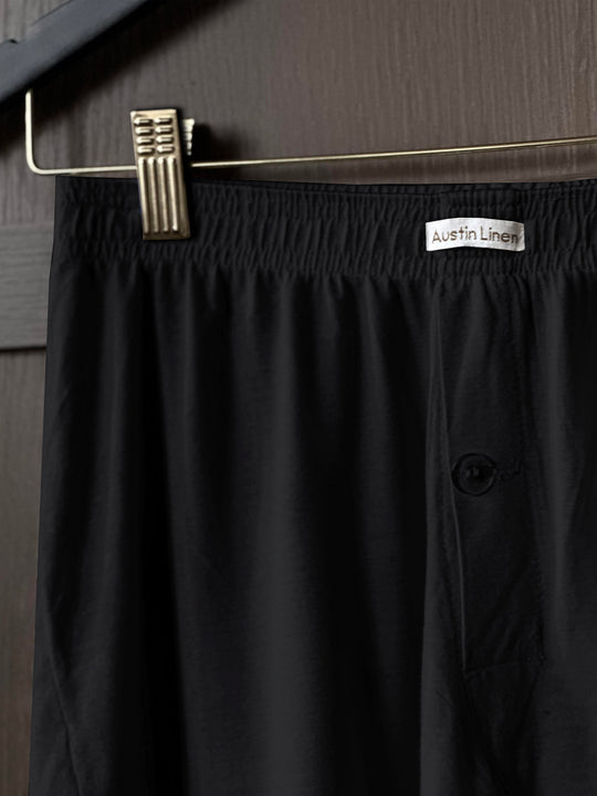 Black boxer briefs with a visible brand label on a hanger against a neutral background