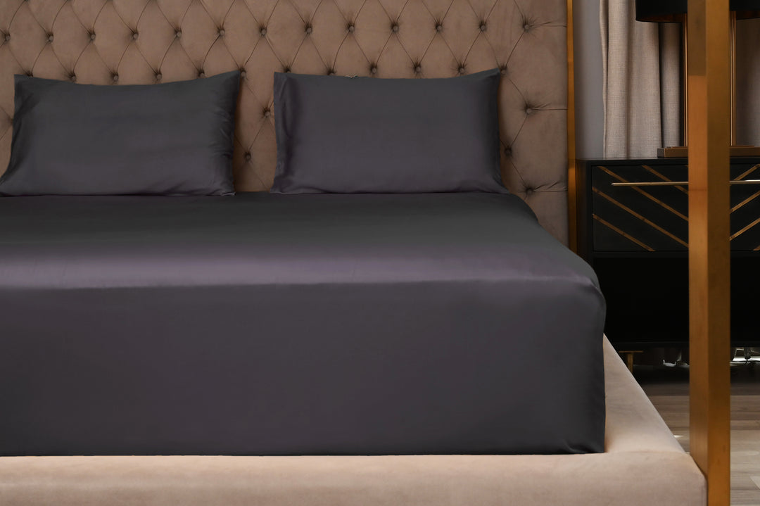 Gray bedding set on a bed with a tufted headboard.
