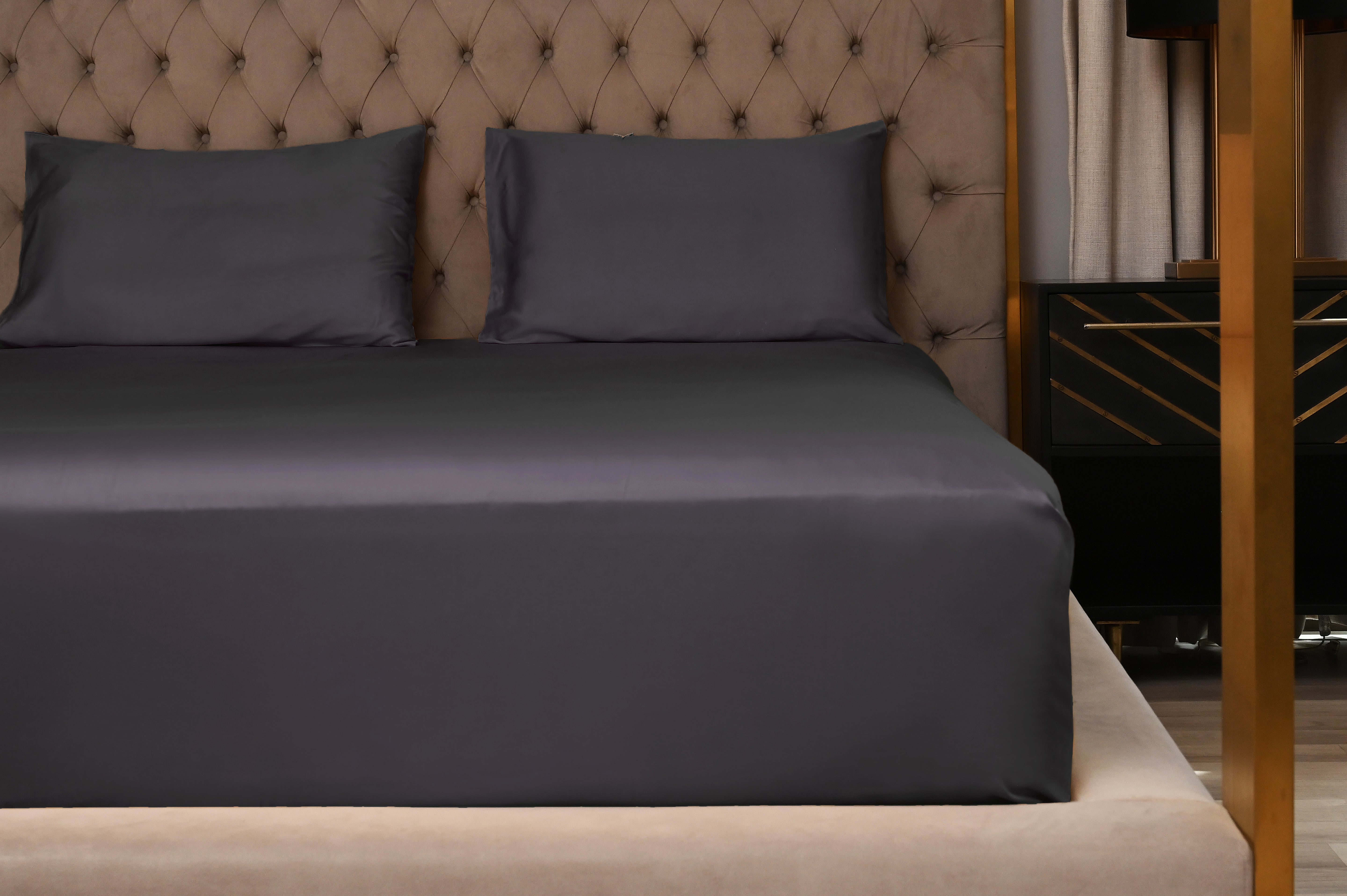 Gray bedding set on a bed with a tufted headboard.