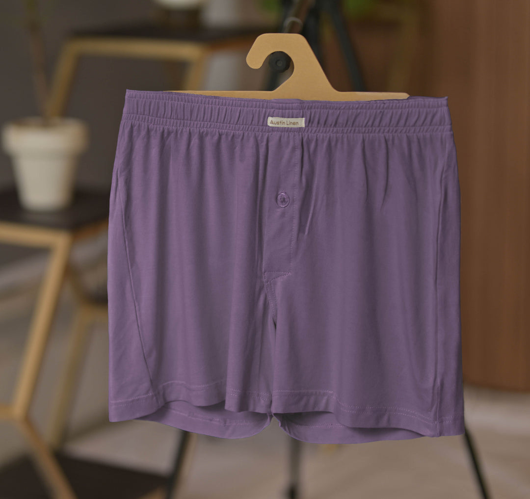 Purple boxer briefs on a hanger with a blurred indoor background