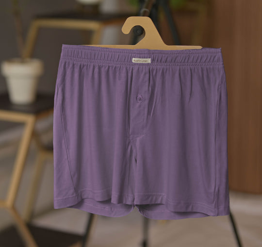 Purple boxer briefs on a hanger with a blurred indoor background