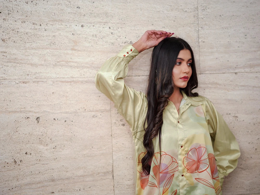 Woman wearing a light green floral blouse against a textured wall.